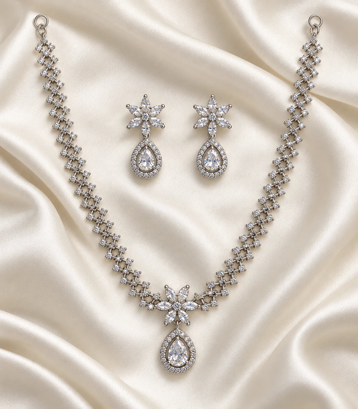 Silver clear star teardrop necklace and matching earring pair arranged on cream fabric