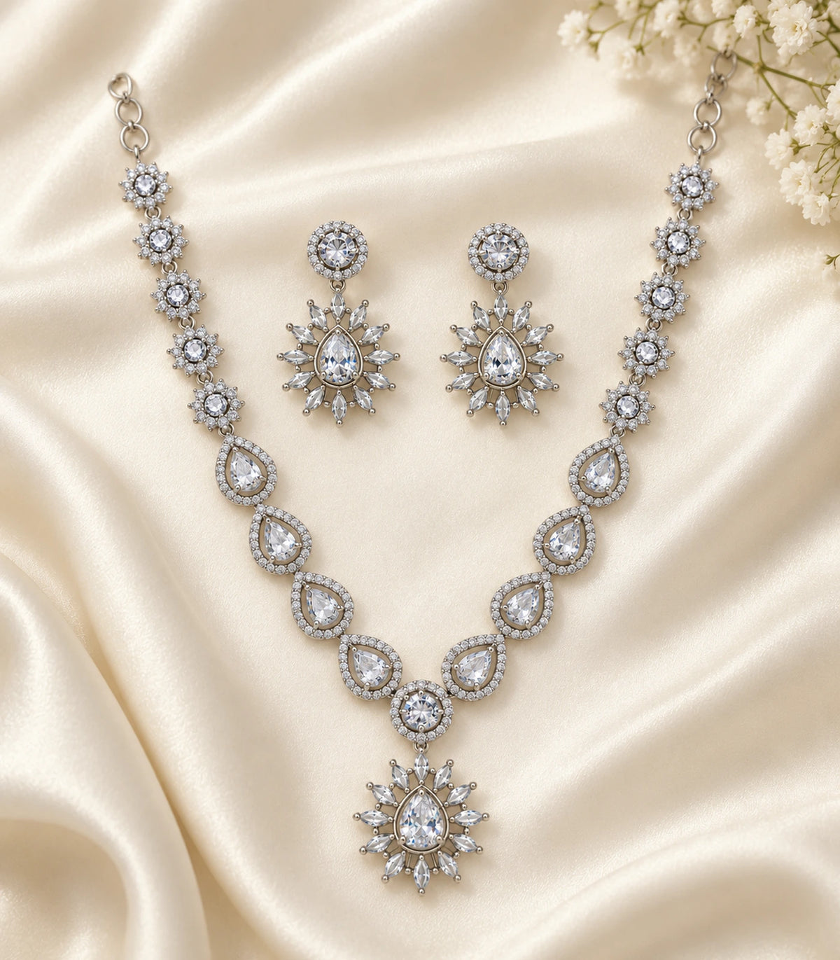 Silver Clear Teardrop Sunburst Crystal Necklace Set and matching earrings arranged on ivory fabric