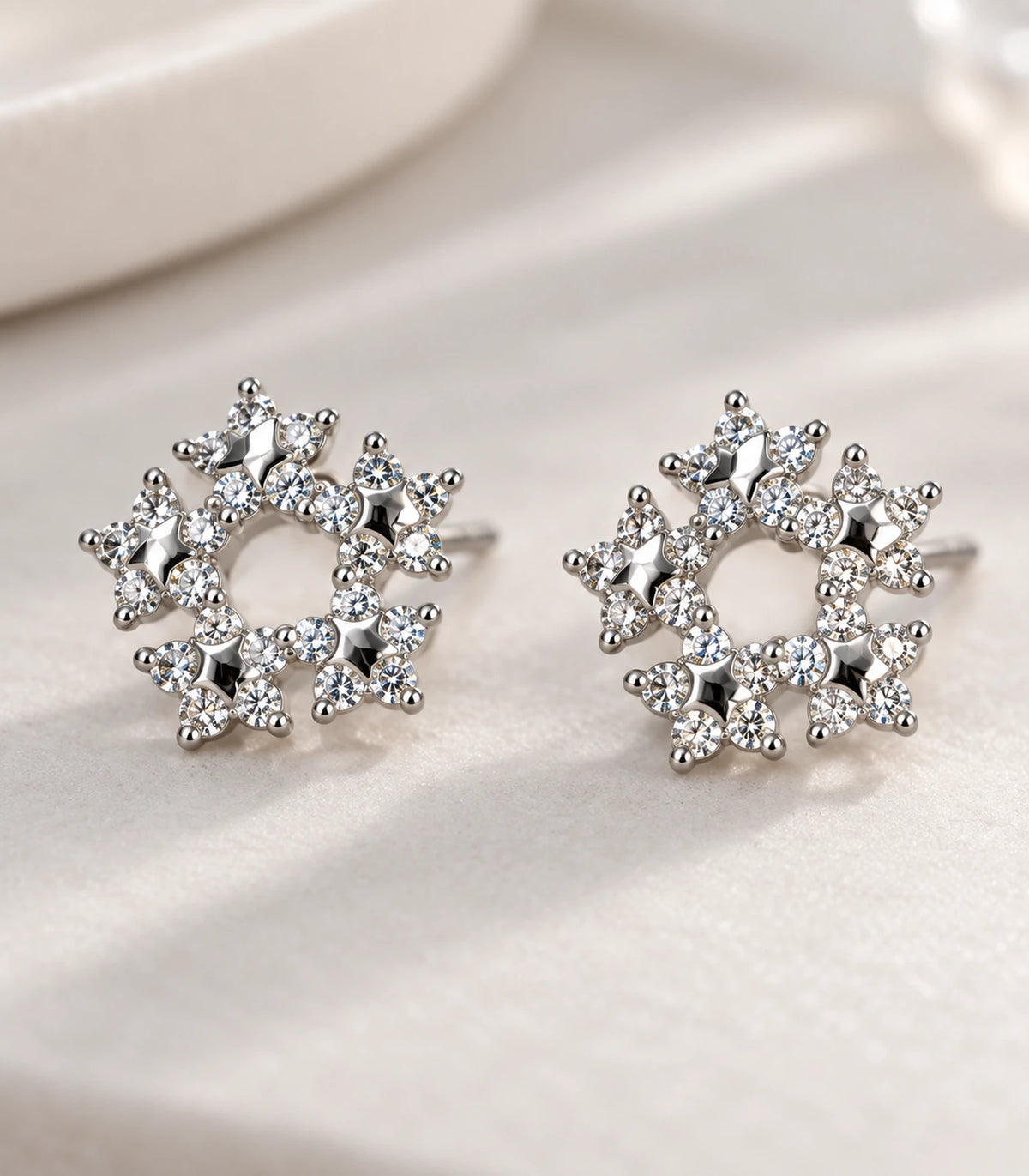 Close view of the matching silver-tone butterfly wreath stud earrings on light fabric