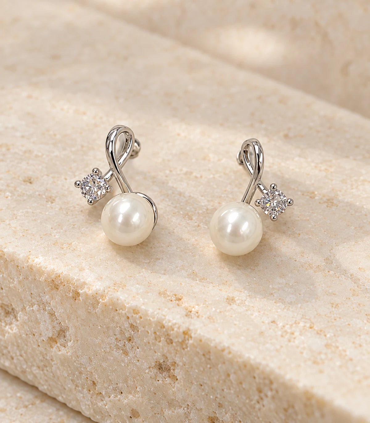 Pair of silver-tone loop earrings photographed close up on pale stone