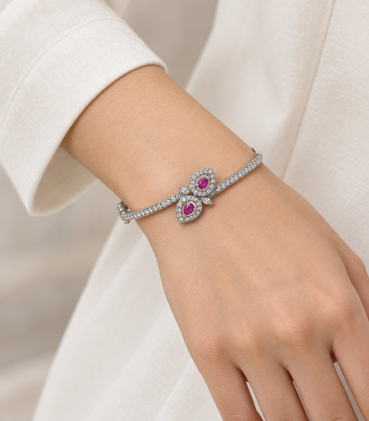 Silver magenta double leaf bangle worn on a wrist with an ivory sleeve