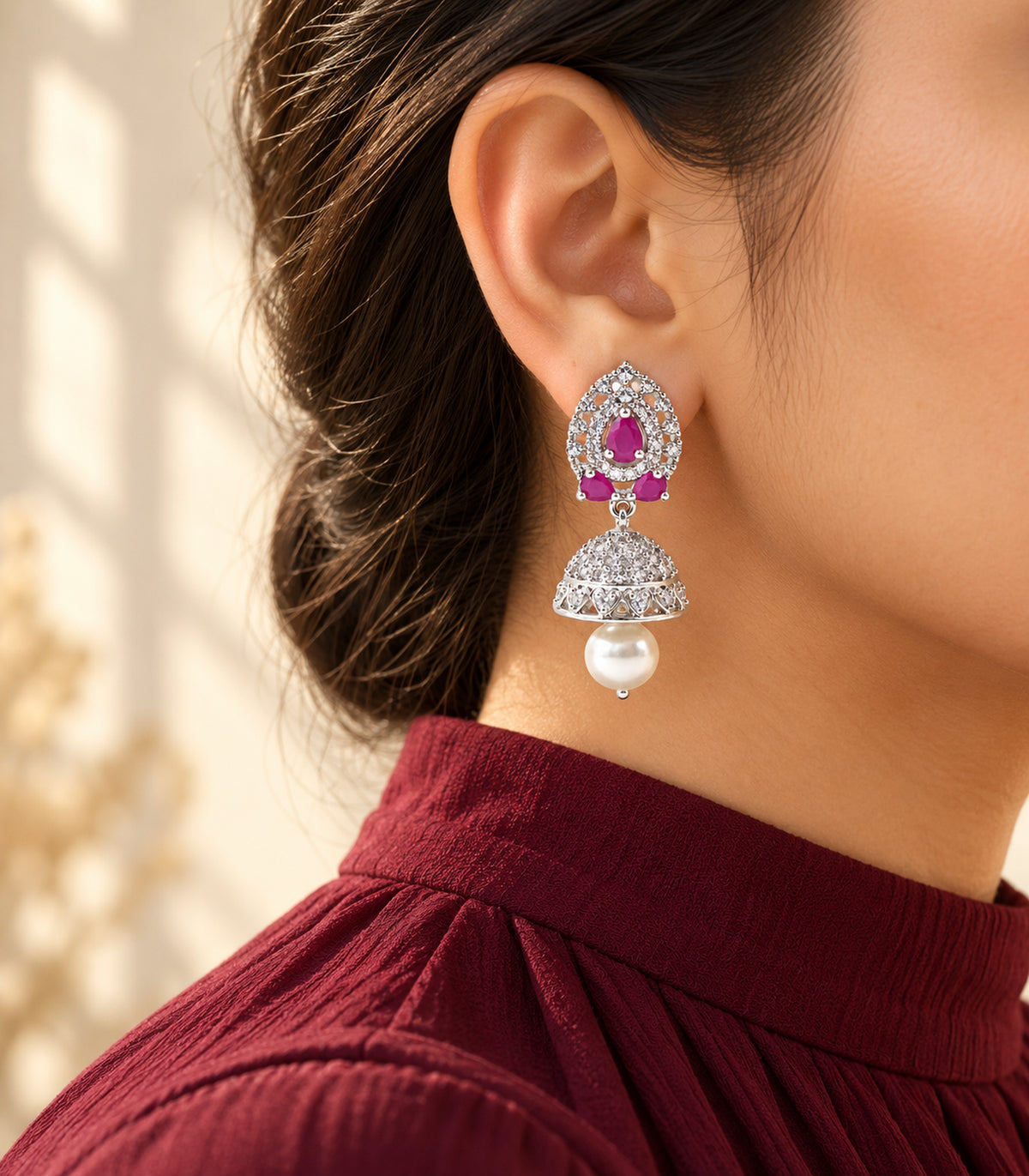 Silver-tone magenta lattice jhumka earring worn beside a burgundy high neckline