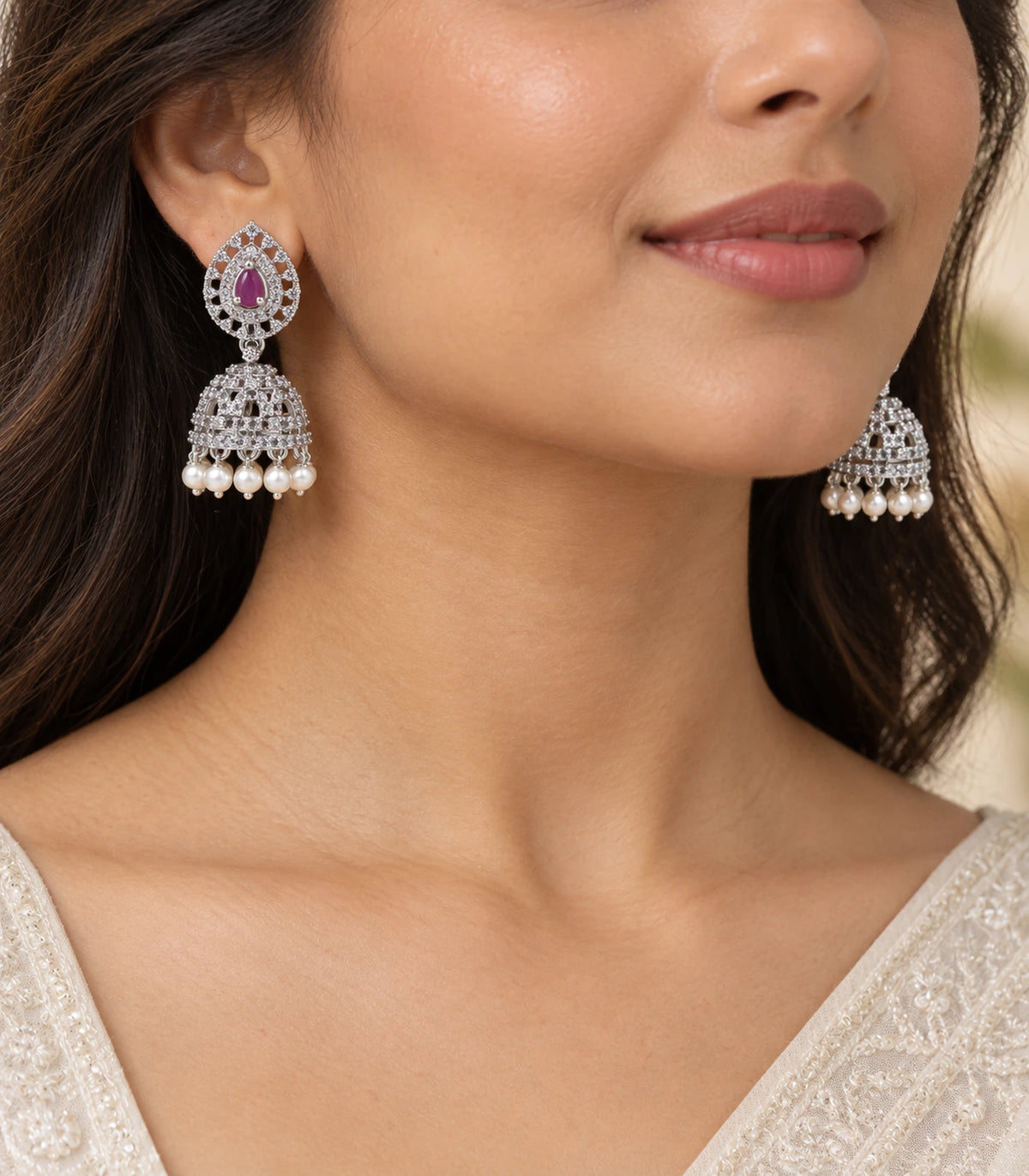 Close view of the silver-tone magenta openwork pearl-fringe jhumka earring pair worn