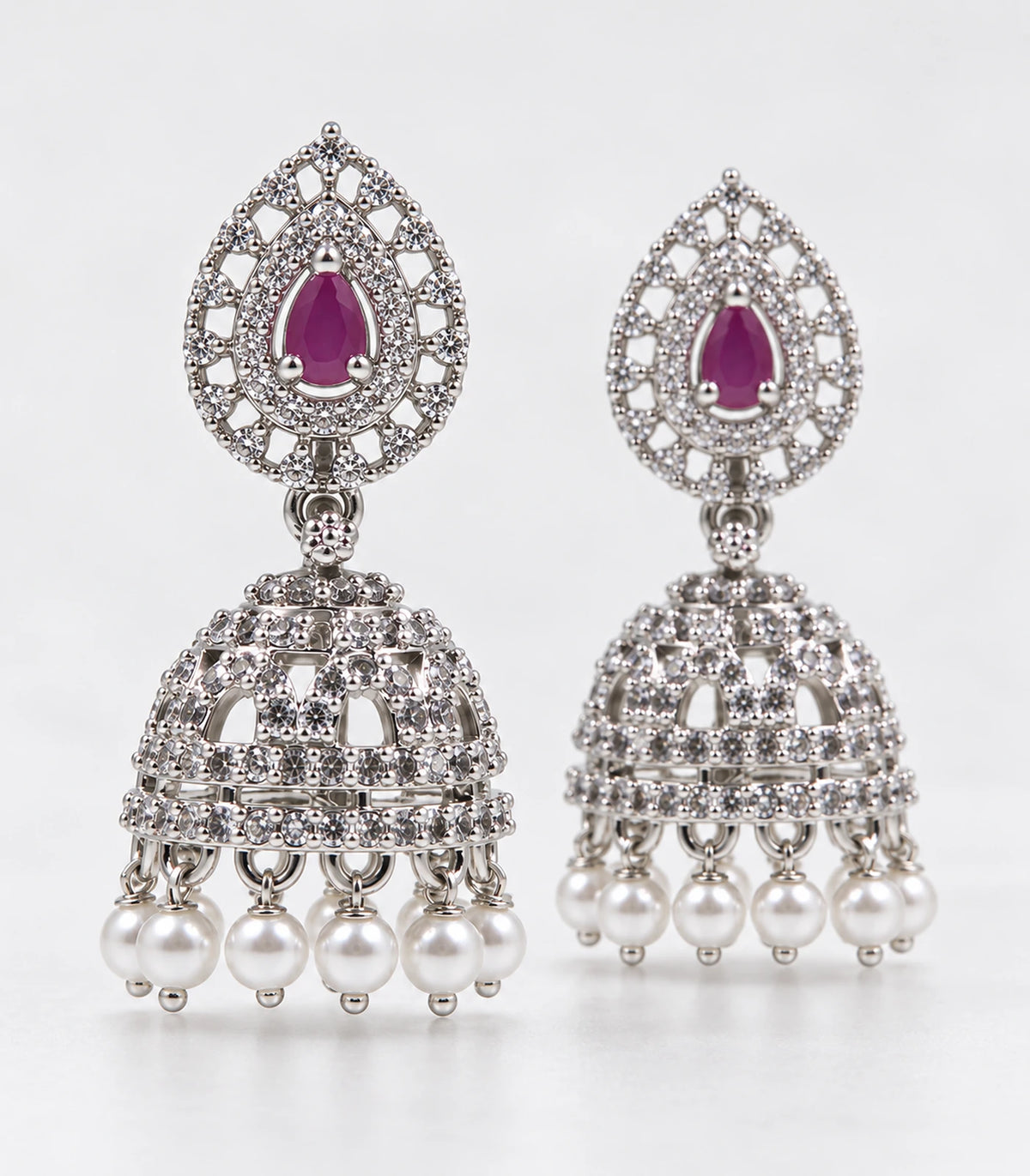 Silver-tone magenta openwork jhumka earring pair with white pearl-look fringe in a styled product view