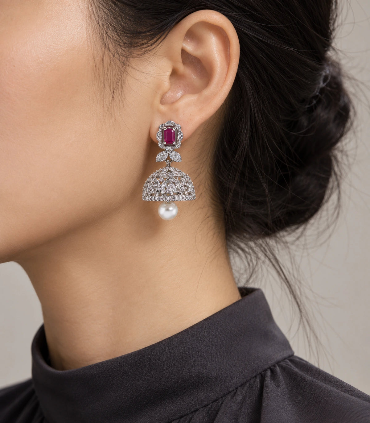 Silver-tone magenta rectangular bow pearl-style jhumka earring worn in side view