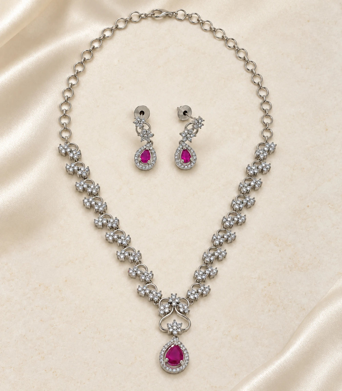 Silver Magenta Teardrop Necklace Set with two earrings arranged on a cream surface