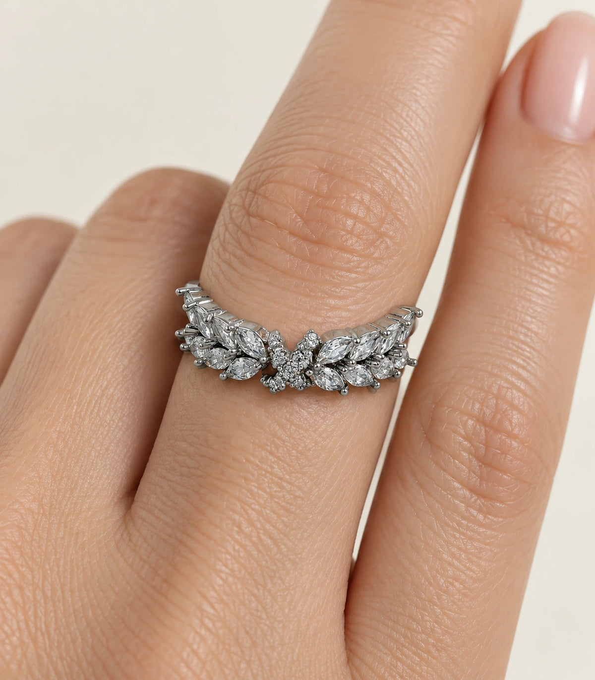 Closeup of silver marquise leaf wing ring with clear stones worn on a finger