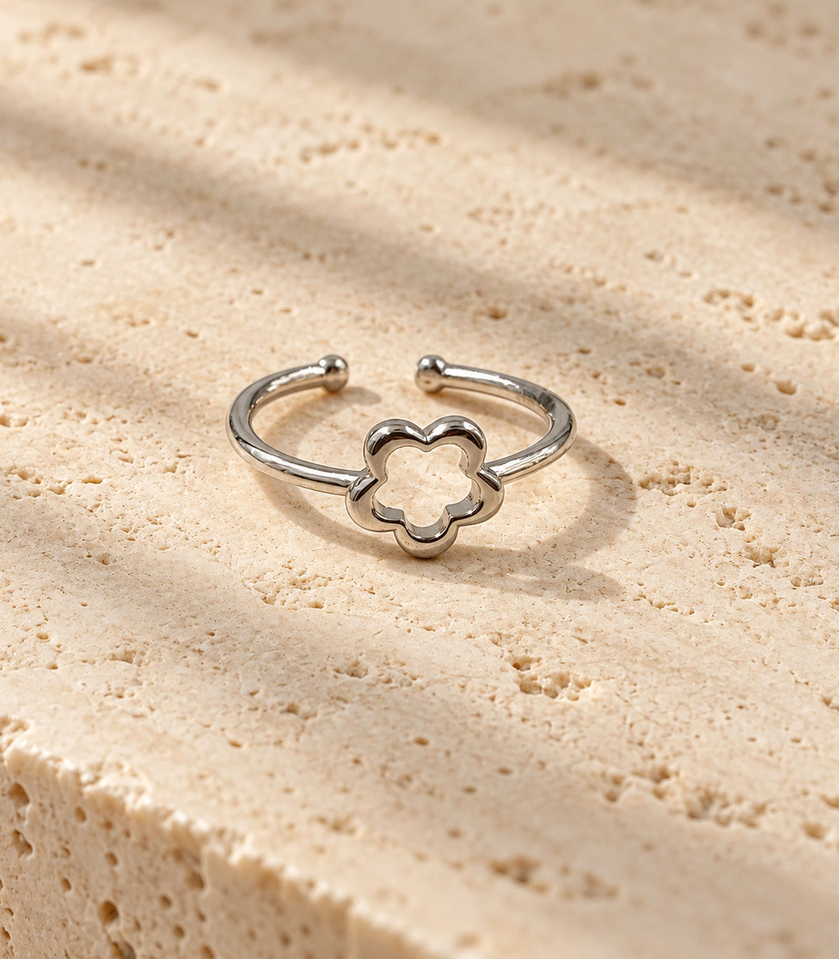One complete silver-tone open flower ring styled on a pale stone surface