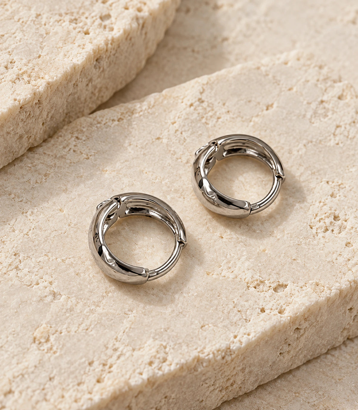 JIMIKI Silver Organic Polished Huggie Earrings — editorial flat lay #color_silver