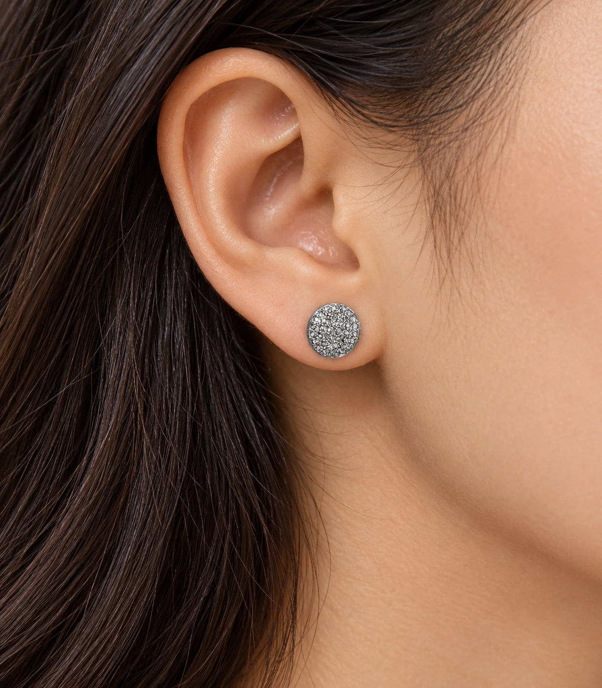 Silver-tone round pavé disc stud earring worn on an ear