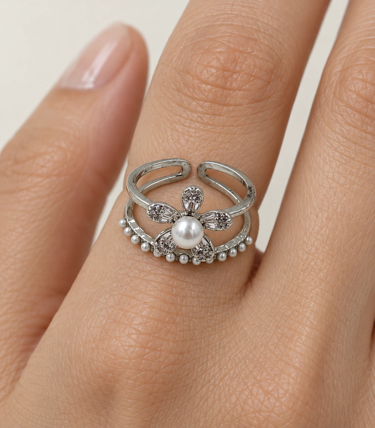 Close view of the pearl-centred flower and fringe on the silver-tone open ring