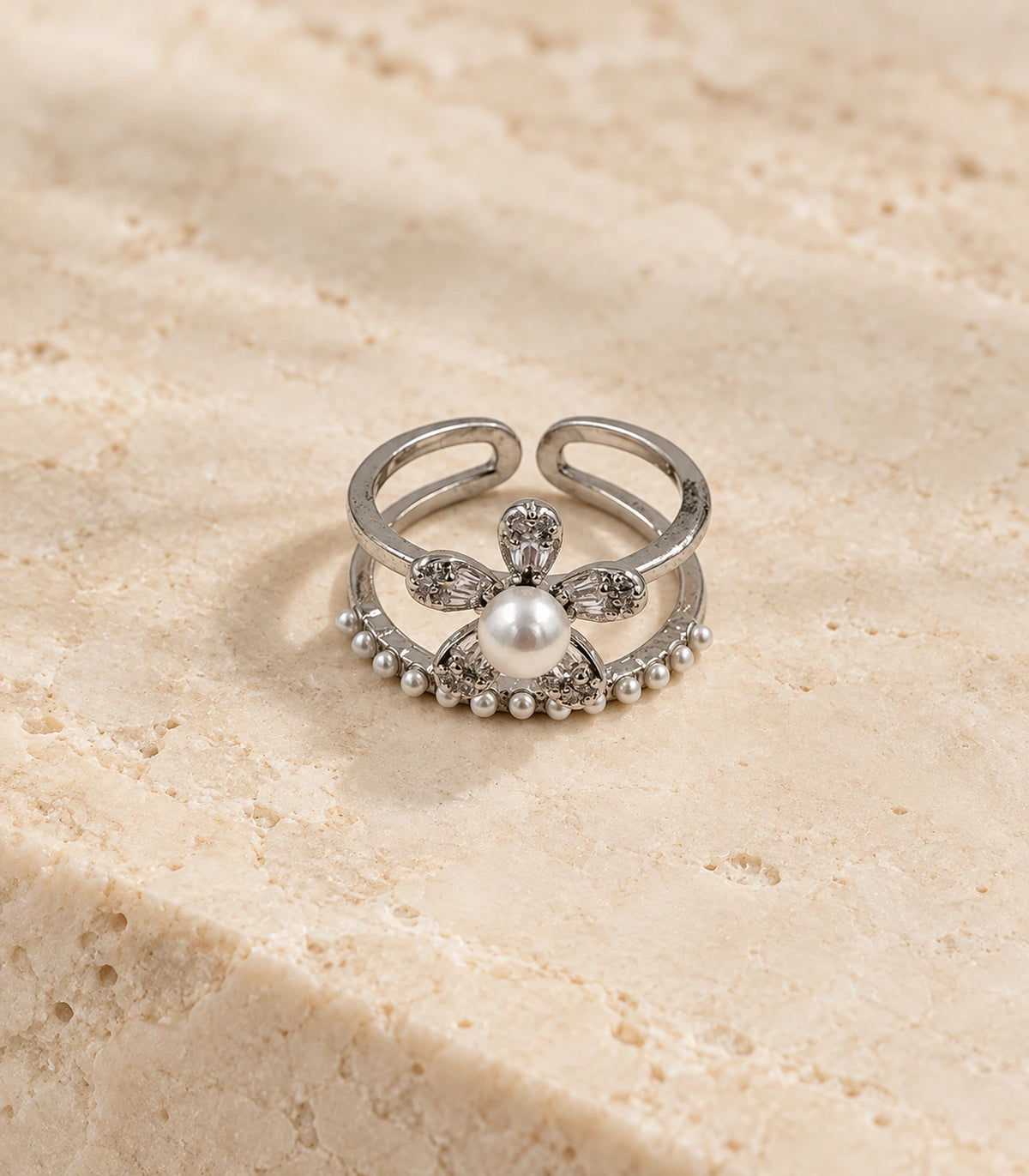 Silver-tone pearl flower fringe open ring on a beige stone surface