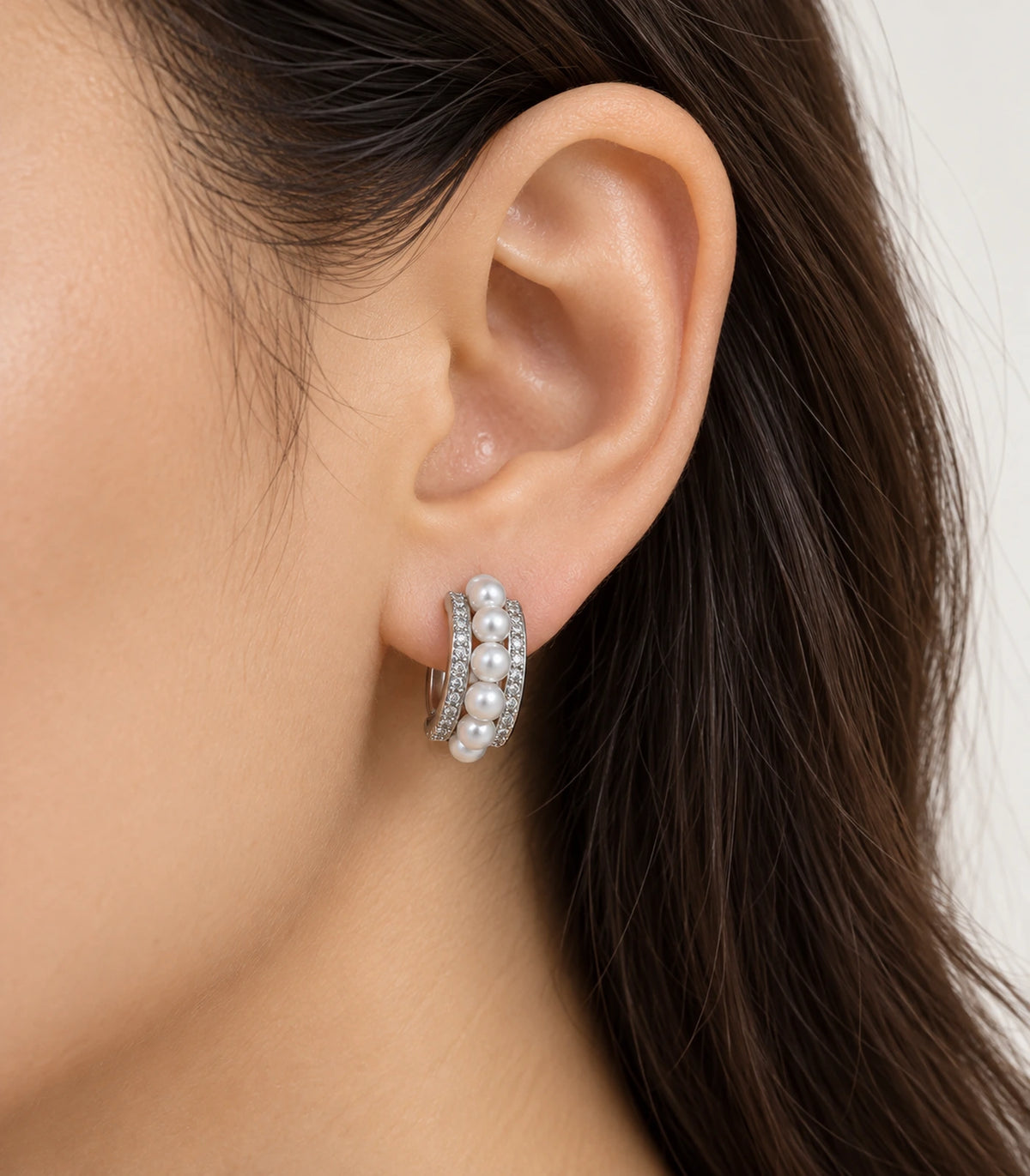 Silver-tone pearl and pavé triple-row huggie earring worn on one ear