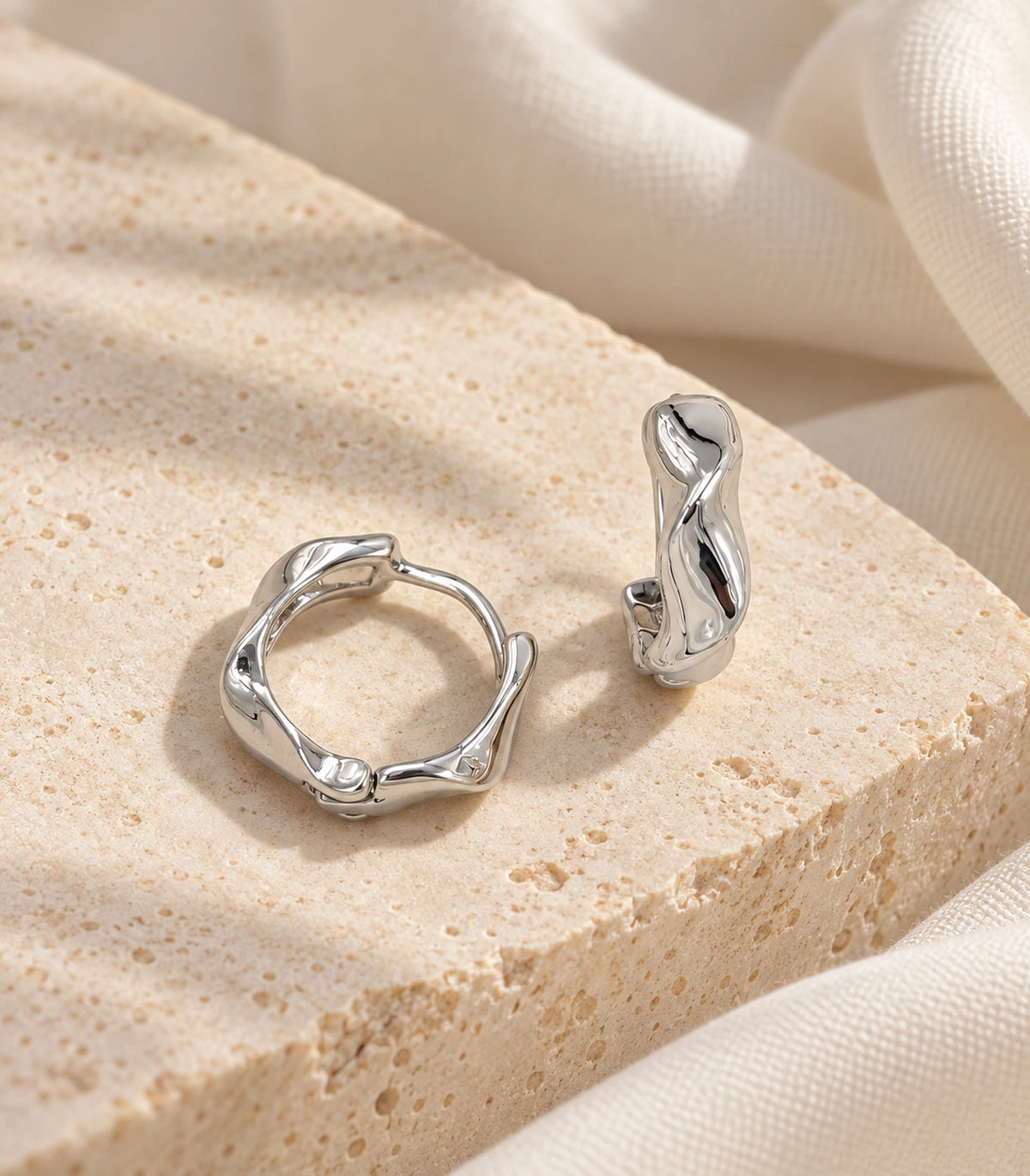 JIMIKI Silver Sculpted Twist Hoop Earrings - editorial flatlay #color_silver