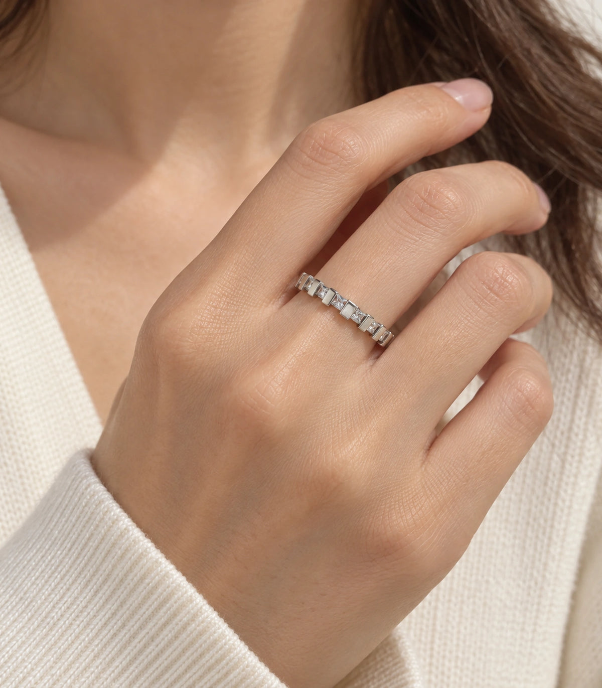 Silver square crystal bar pattern ring in a distinct hand-near-neck pose