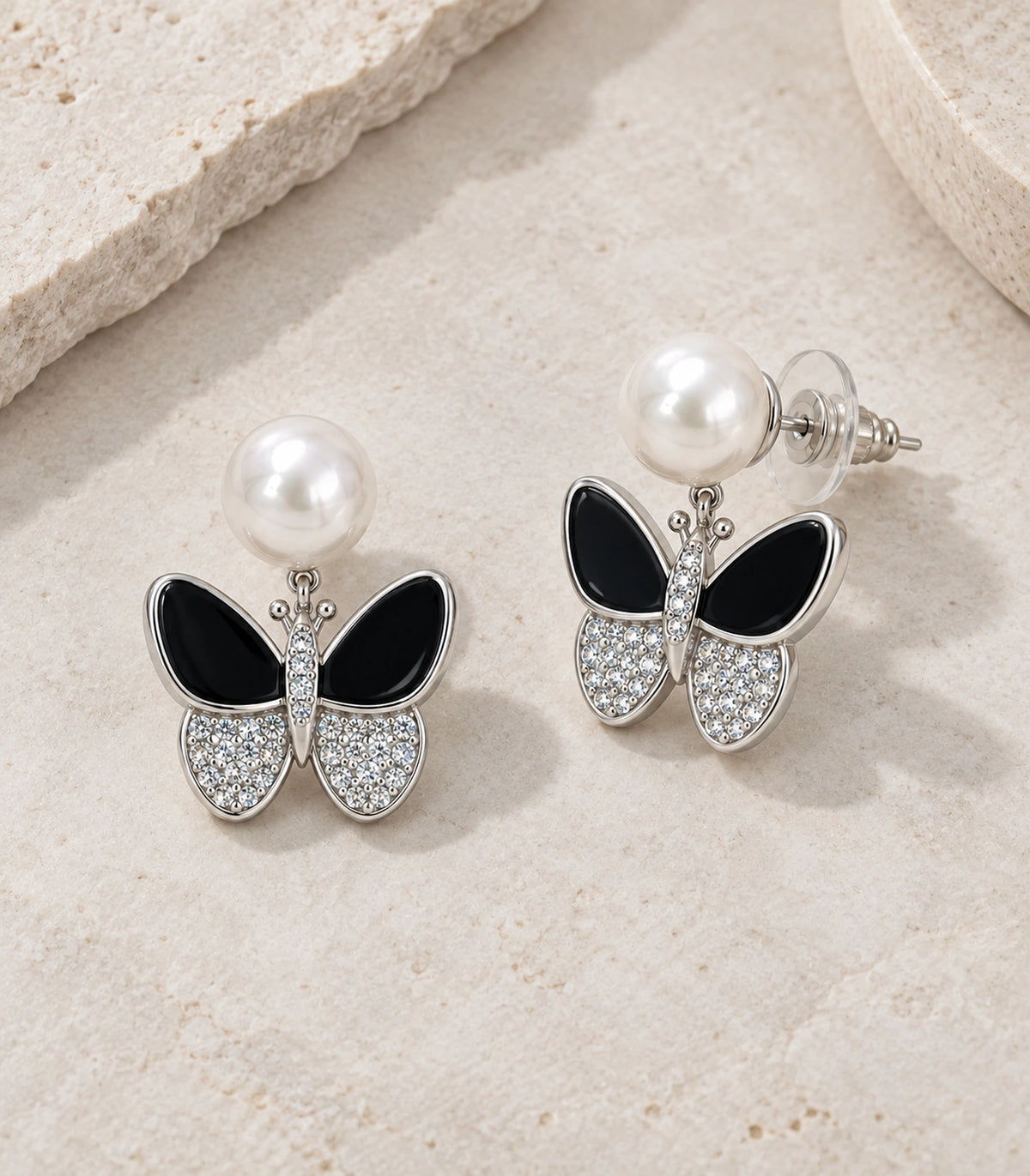 JIMIKI Silver Tone Black Enamel Butterfly Pearl Stud Earring Pair in Black / White Pearl / Silver, editorial flat lay