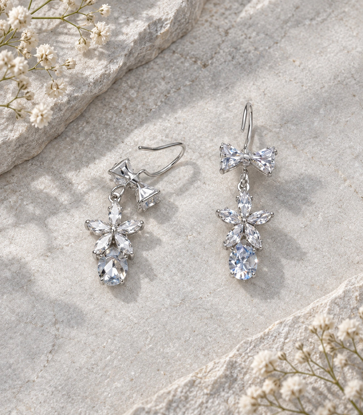 JIMIKI Silver-Tone Bow Flower Pear Drop Earrings in Silver-tone / clear, editorial flat lay