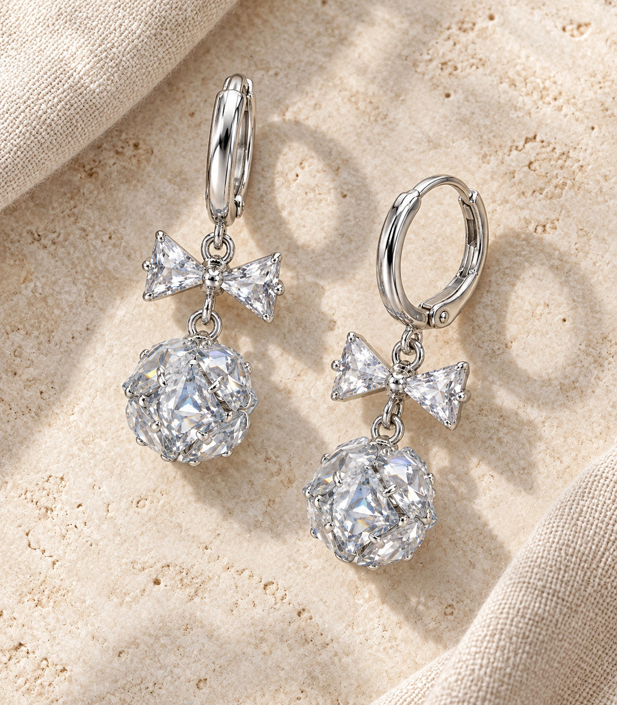 JIMIKI Silver Tone Clear Crystal Bow Cluster Ball Hoop Earring Pair in Silver tone / clear, editorial flat lay