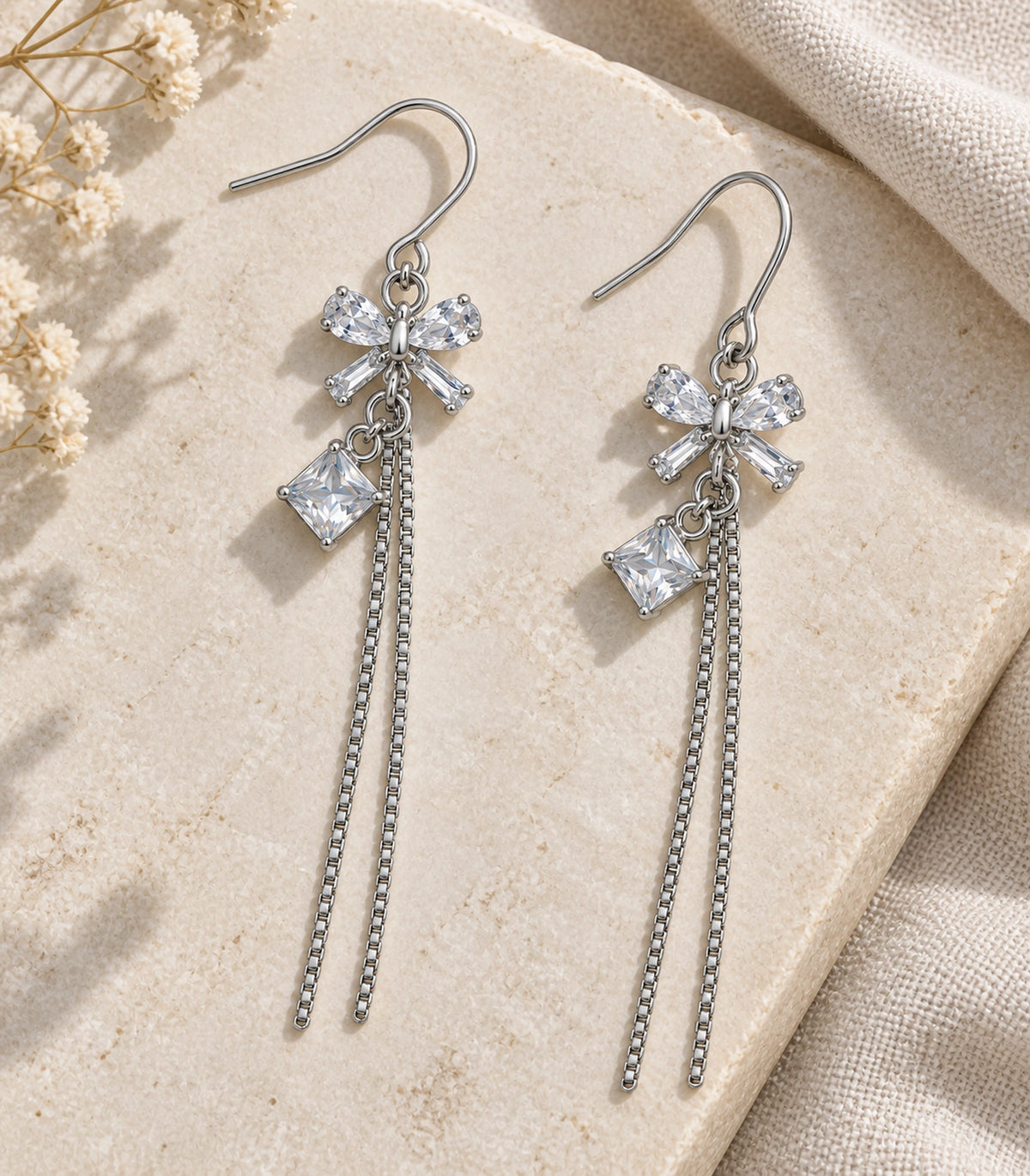 JIMIKI Silver Tone Clear Crystal Bow Square Chain Tassel Earring Pair in Silver tone / clear, editorial flat lay