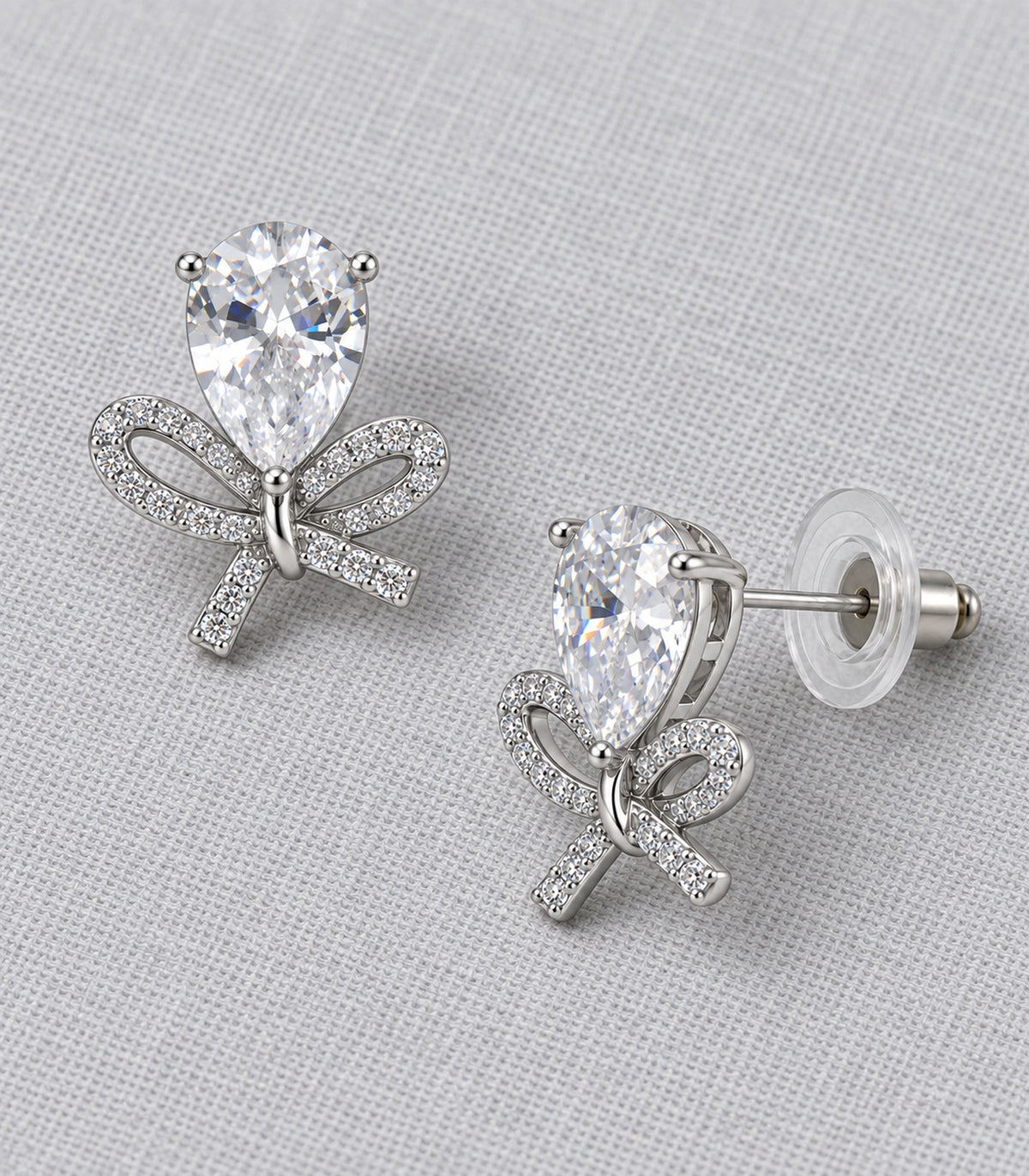 JIMIKI Silver Tone Clear Pear Crystal Bow Stud Earring Pair in Silver-tone, editorial flat lay