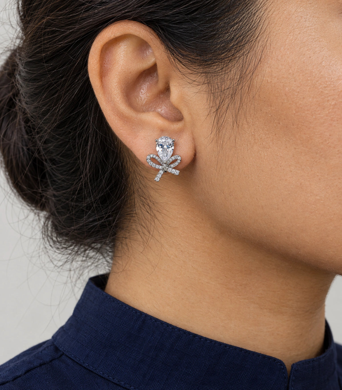 JIMIKI Silver Tone Clear Pear Crystal Bow Stud Earring Pair in Silver-tone, model wearing view