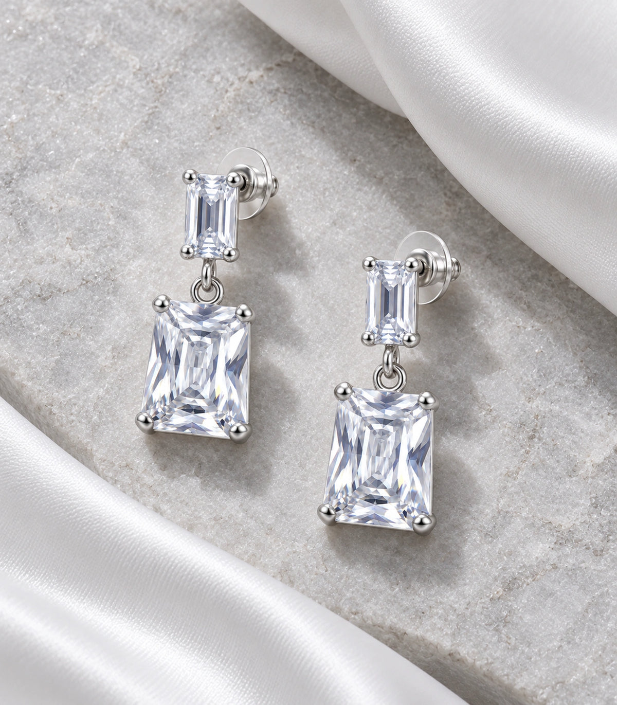JIMIKI Silver Tone Clear Step Cut Two Stone Drop Earring Pair in Clear / Silver, editorial flat lay