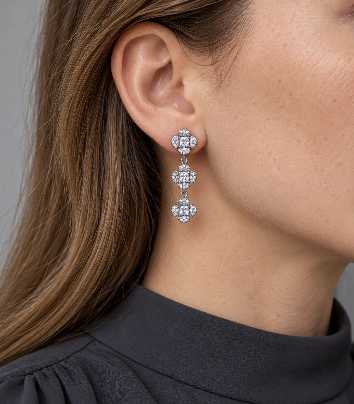 JIMIKI Triple Four Petal Flower Drop Earring Pair in Silver tone / clear, model wearing view #color_silver tone / clear