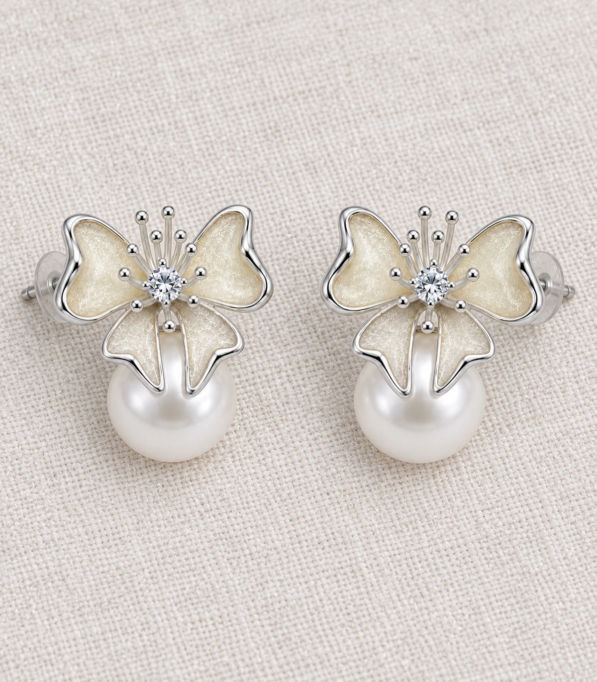 JIMIKI Butterfly Pearl Stud Earring Pair in Silver Tone / Cream, editorial flat lay #color_silver tone / cream