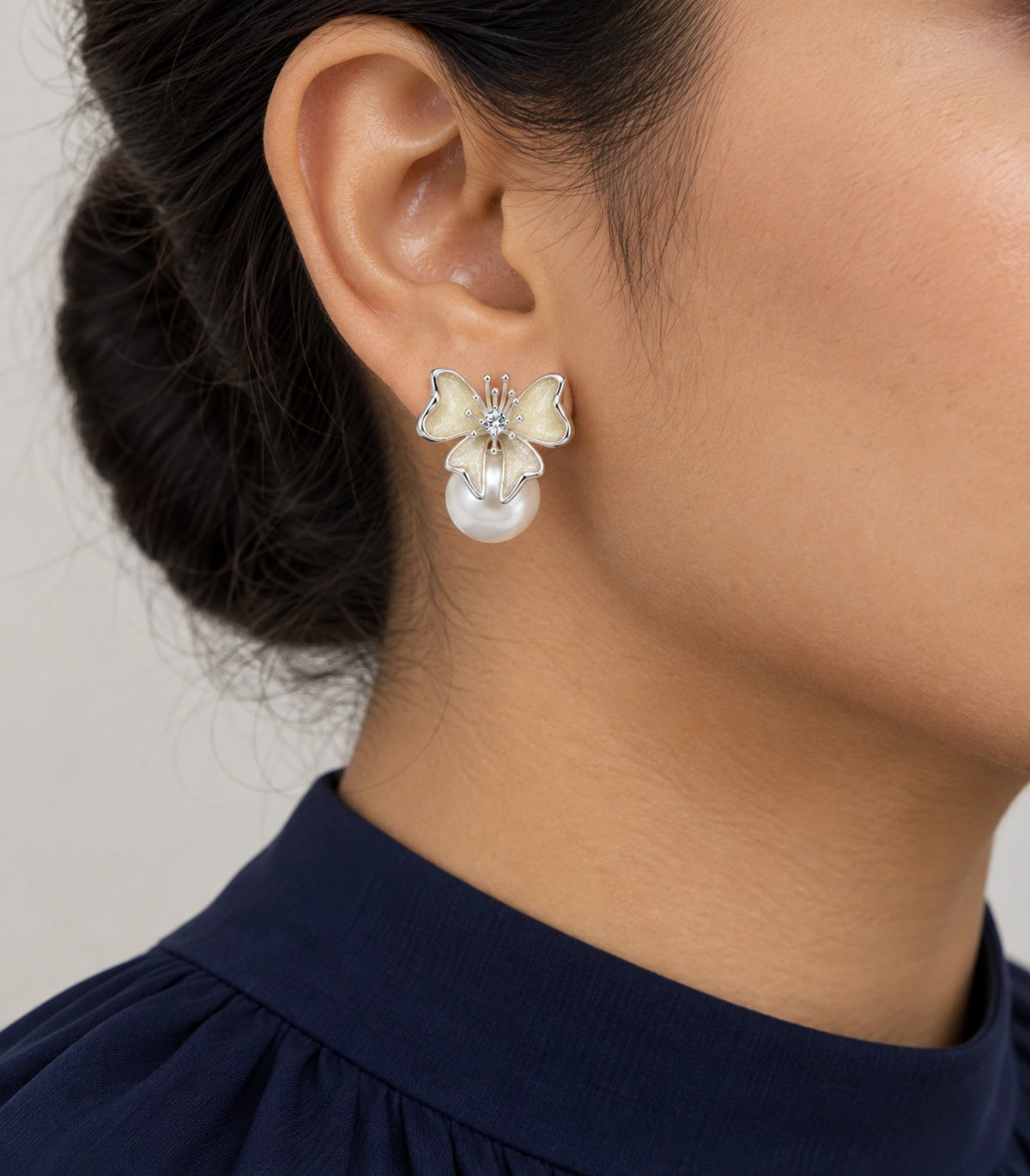 JIMIKI Butterfly Pearl Stud Earring Pair in Silver Tone / Cream, model wearing view #color_silver tone / cream