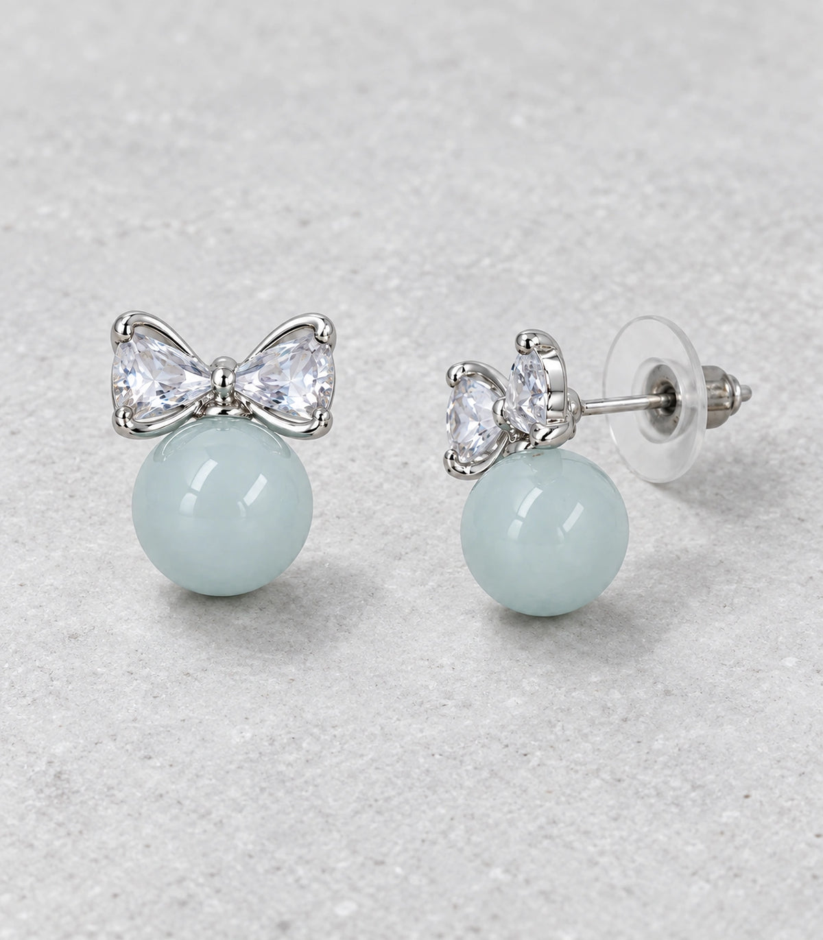 JIMIKI Silver-Tone Crystal Bow Blue Bead Stud Earrings in Silver-tone / pale blue, editorial flat lay