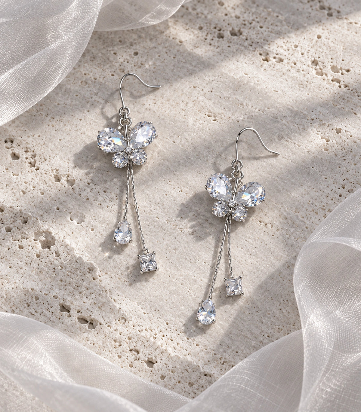 JIMIKI Silver Tone Crystal Butterfly Pear Square Chain Earring Pair in Silver-tone, editorial flat lay