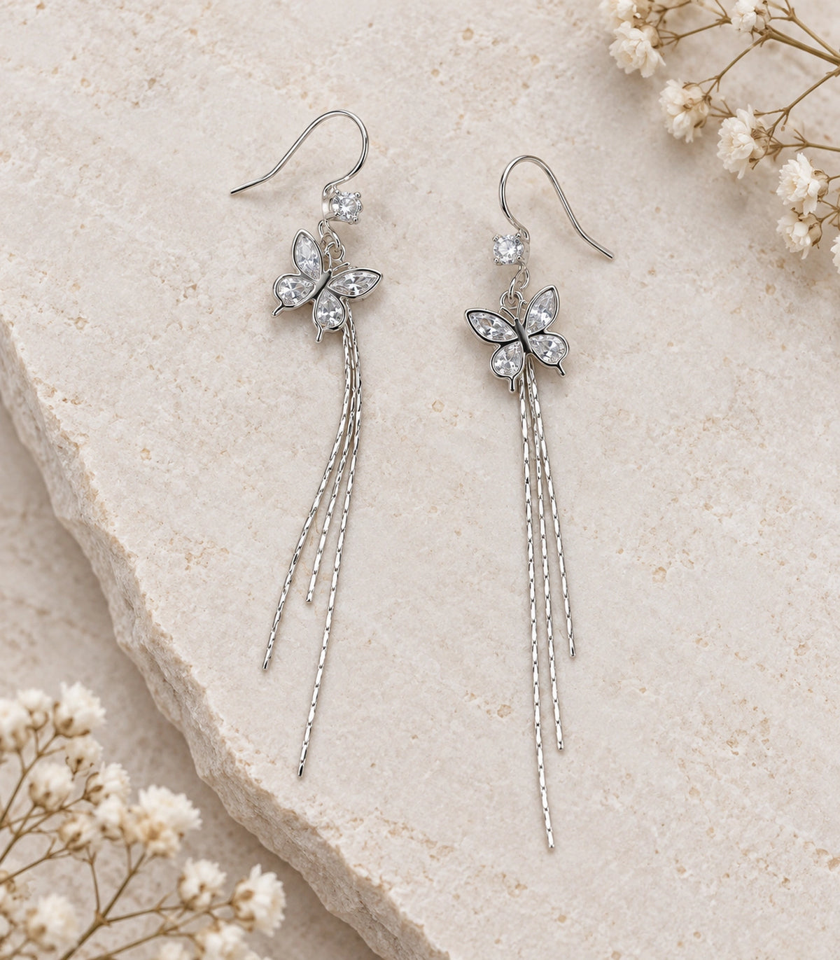 JIMIKI Silver Tone Crystal Butterfly Three Chain Earring Pair in Silver-tone, editorial flat lay