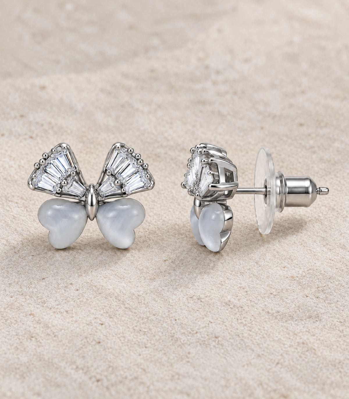 JIMIKI Crystal Wing Butterfly Stud Earring Pair in Silver Tone, editorial flat lay #color_silver tone