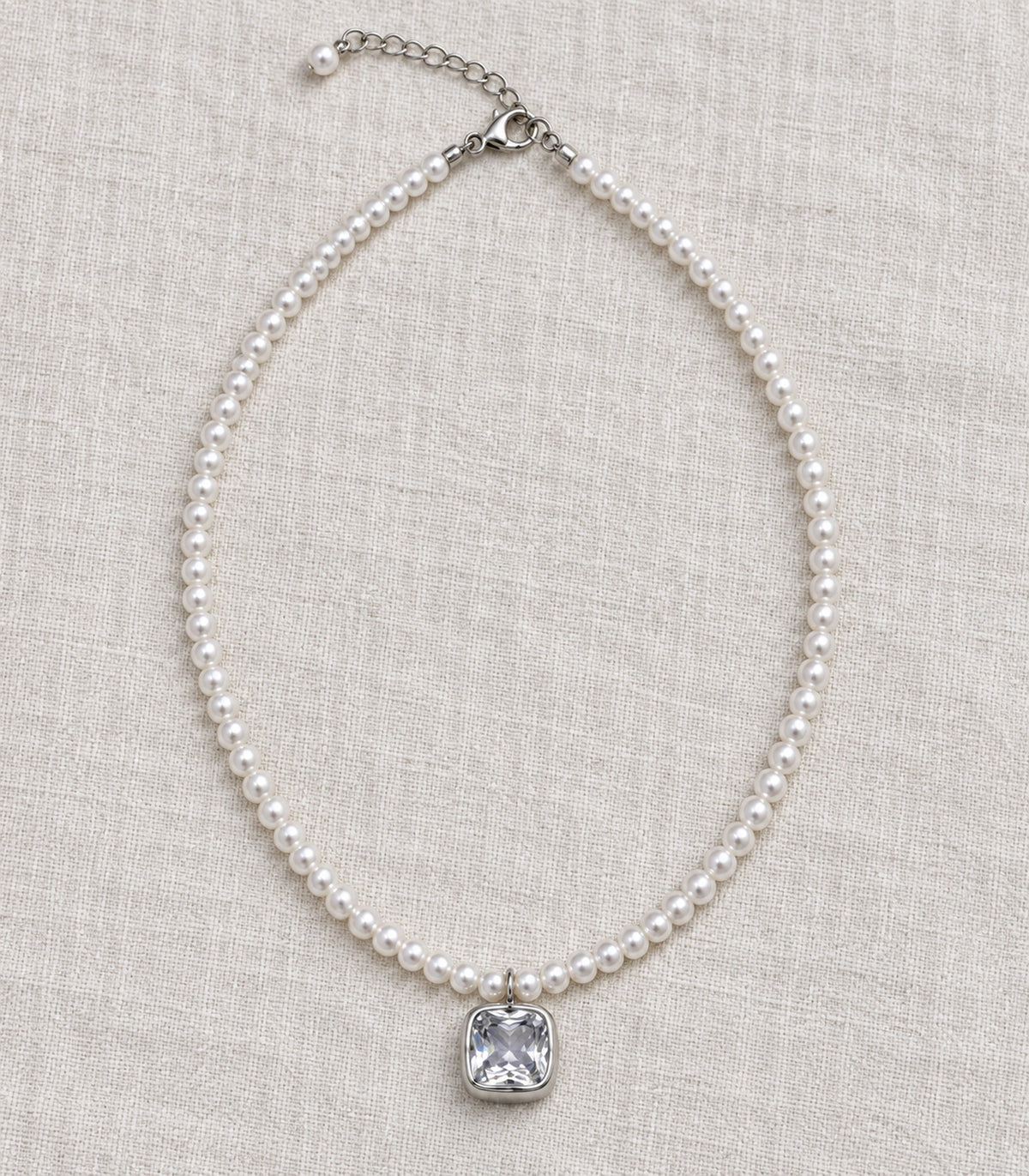 JIMIKI Silver Tone Cushion Crystal Pearl Style Necklace in Silver tone / white, editorial flat lay