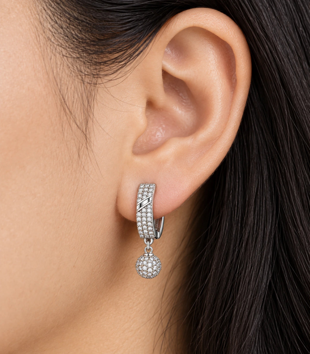 JIMIKI Silver-Tone Diagonal Pavé Ball Drop Huggie Earrings — close-up of the earring design #color_silver-tone / clear