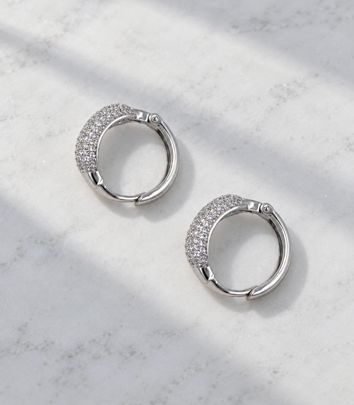 JIMIKI Silver-Tone Domed Pave Hinged Hoop Earring Pair in Silver Tone, editorial flat lay