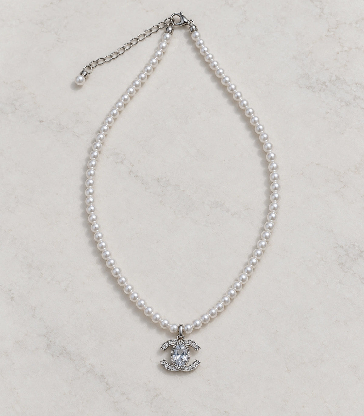 JIMIKI Silver-Tone Double-C Crystal Pearl Necklace in Silver-tone / clear / white, arranged in an editorial flat lay