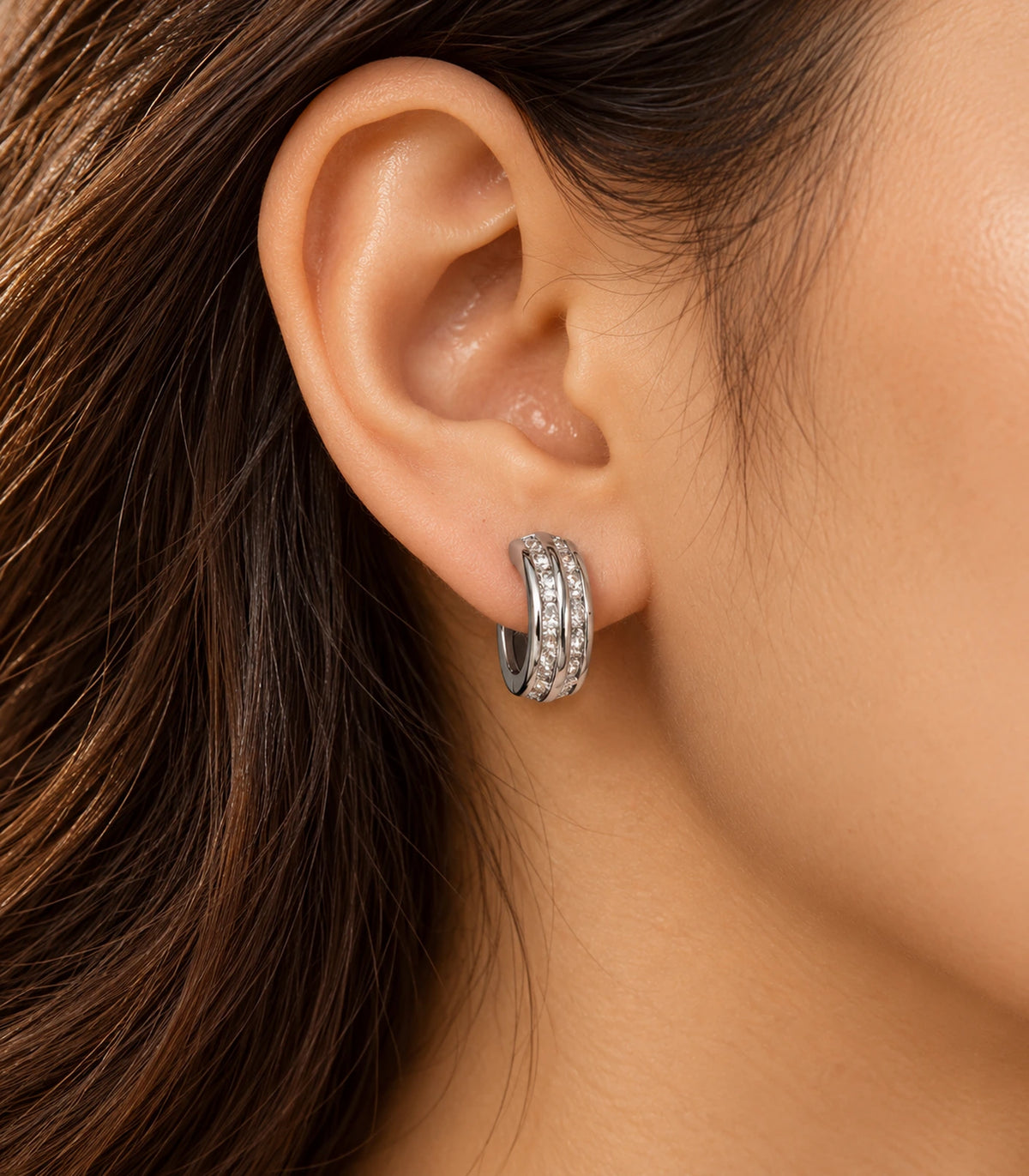 JIMIKI Silver Double Channel Crystal Huggie Hoop Earrings, worn in warm editorial lighting #color_silver
