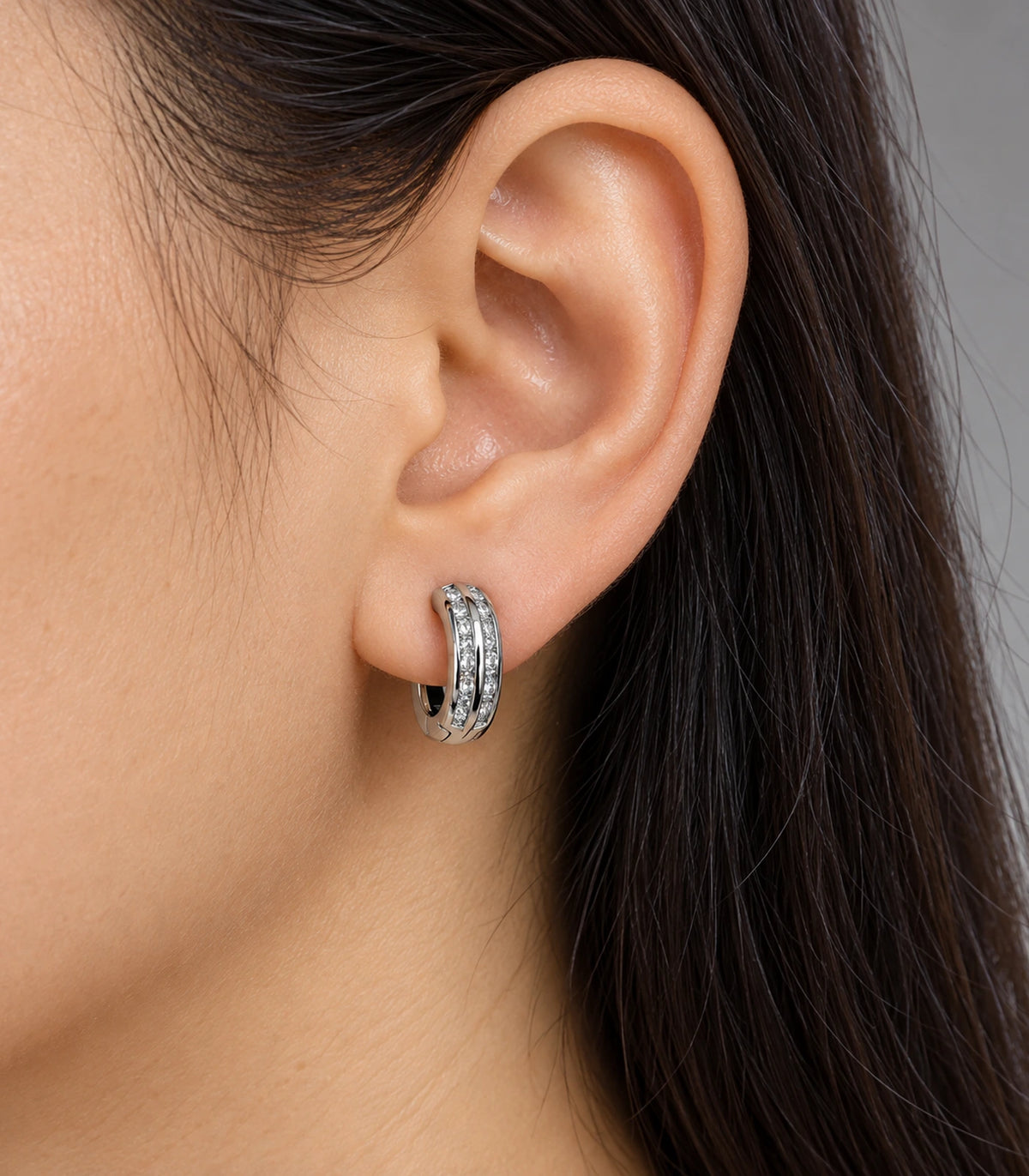 JIMIKI Silver Double Channel Crystal Huggie Hoop Earrings, shown worn on the ear #color_silver