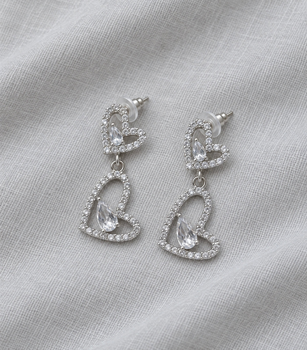 JIMIKI Double Heart Pear Crystal Drop Earrings in Silver Tone, editorial flat lay #color_silver tone