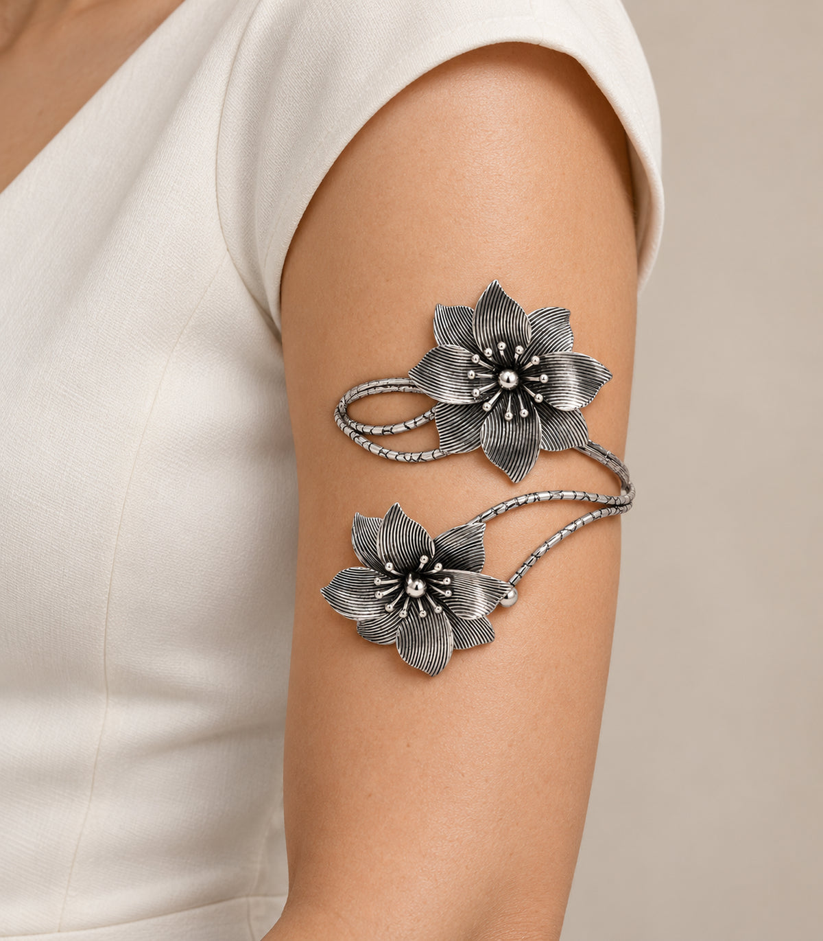 Silver-tone double-flower arm cuff worn on the upper arm with an ivory outfit