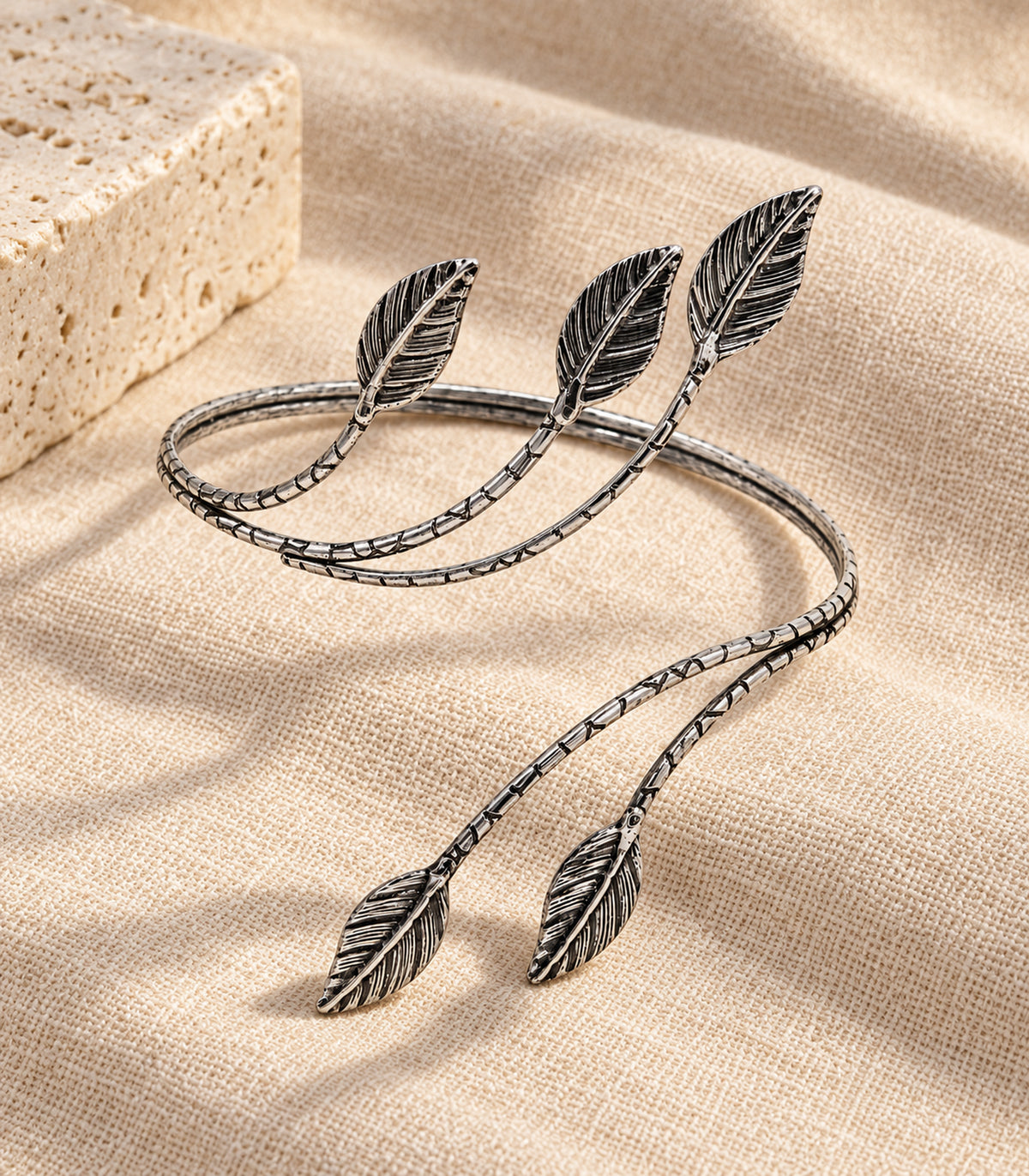 Complete single five-leaf silver-tone arm cuff arranged on linen