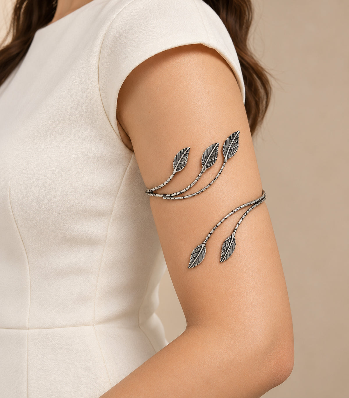 Silver-tone five-leaf branch cuff worn on the upper arm with ivory clothing