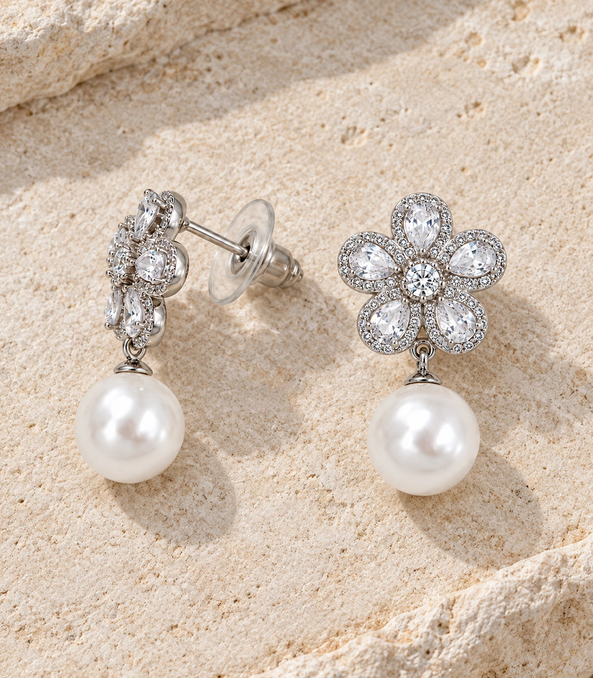 JIMIKI Five Petal Crystal Flower Pearl Drop Earring Pair in Silver-tone, editorial flat lay #color_silver-tone