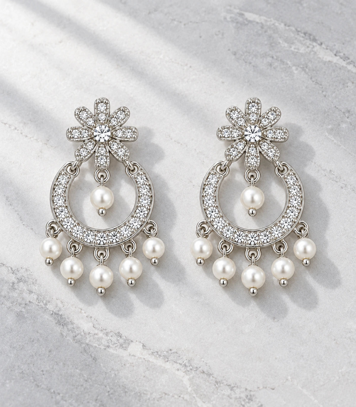 JIMIKI Silver-Tone Flower Pearl Chandbali Earrings — pair in a styled flat lay #color_silver-tone / white