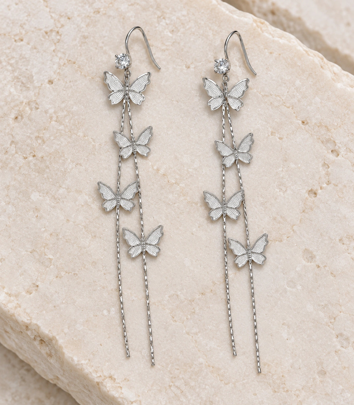 JIMIKI Silver Tone Four Butterfly Chain Earring Pair in Silver-tone, editorial flat lay