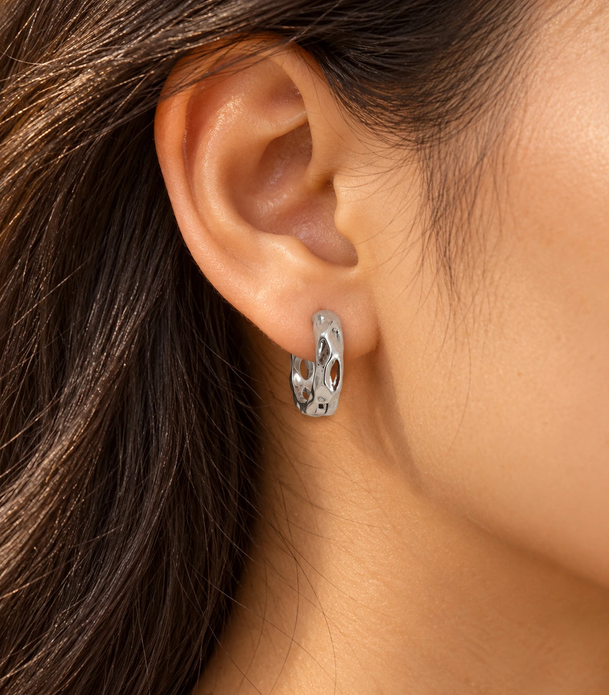 JIMIKI Silver Hammered Marquise Cutout Huggie Hoop Earrings, worn in warm editorial lighting #color_silver