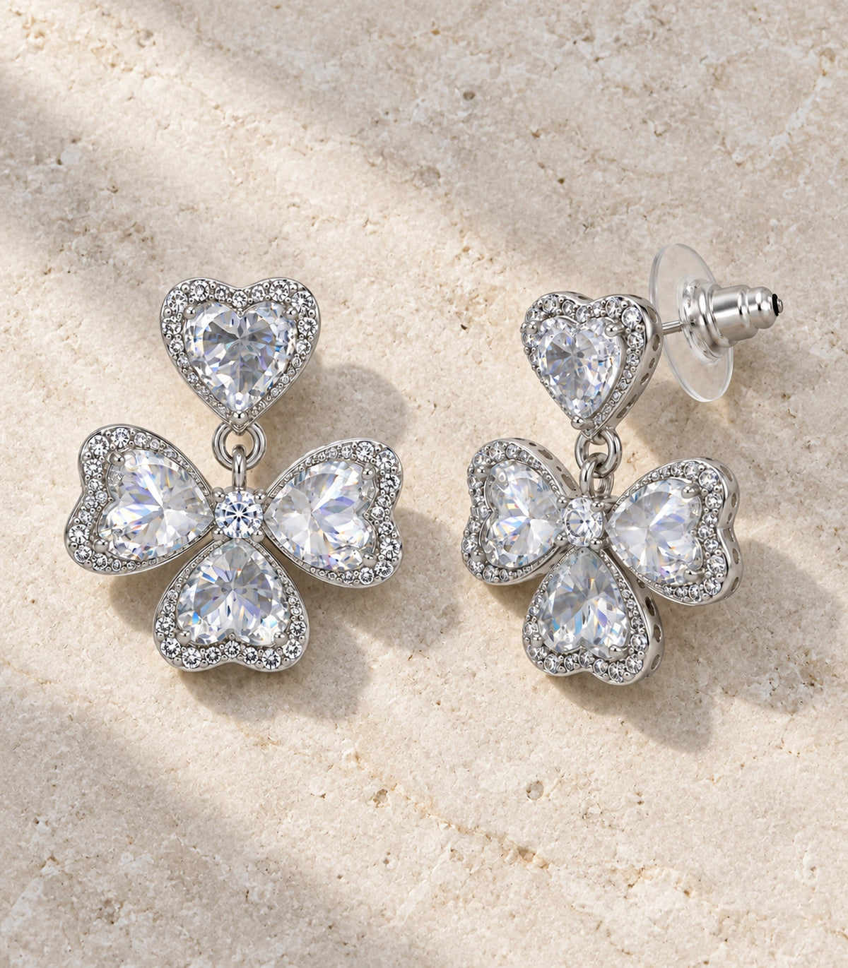 JIMIKI Heart Crystal Three Petal Drop Earring Pair in Silver-tone, editorial flat lay #color_silver-tone
