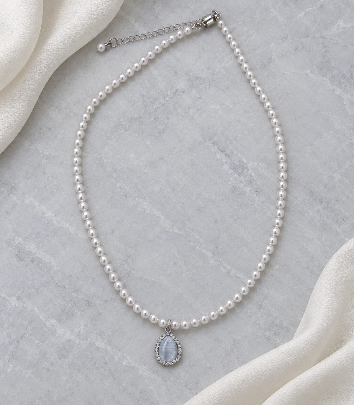 JIMIKI Silver-Tone Icy Blue Teardrop Pearl Necklace in Silver-tone / icy blue, arranged in an editorial flat lay