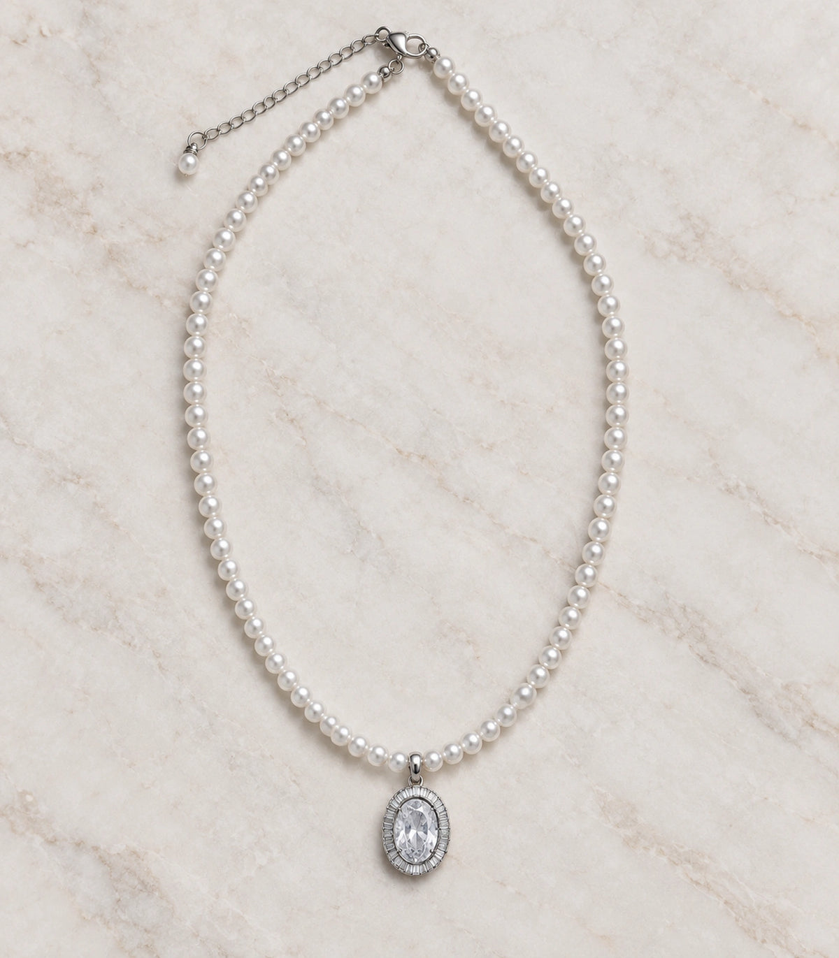 JIMIKI Silver-Tone Oval Baguette Halo Pearl Necklace in Silver-tone / clear / white, arranged in an editorial flat lay